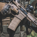 Close-up of a Tactical gear setup with rifle and Magpul PMAG 30 GEN M3 in MCT (Medium Coyote Tan) color, wearing tactical gloves